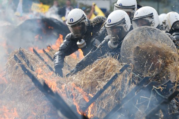 epa04918238 Belgian riot police officers try to extinguish a burning hay barricade as they guard the premises during a European farmers protest rally near the European institutions in Brussels, Belgium, 07 September 2015. Thousands of farmers, many withy their tractors, were gathering on the occasion of an European Agriculture ministers council meeting to vent their anger over economic problems in the agriculture sector and to protest against the decrease of their incomes and the increasing instability they are facing. EPA/LAURENT DUBRULE