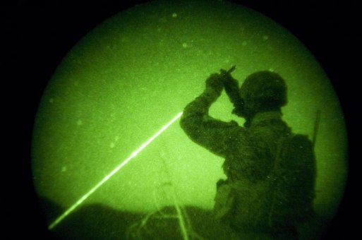 American soldiers with the 173rd battle company, on a battalian-wide mission in the korengal valley, Afghanistan. Through night-vision goggles: JTAC Kevin Caroon, 28, 'sparkles' a target for the AC130 pilots above as he helps control close air support fire from above Yakachina village while on a mission with Battle company in the Korengal Valley. JTACs are Airforce-trained specialists in direct contact with the bomber pilots to call in airstrikes on certain targets while weighing and monitoring collateral damage potential. Captain Dan Kearney, the JTACs, and certain intelligence and communication specialists work as a team from afar but with a bird's eye view to help infantry troops on the ground. October 2007.